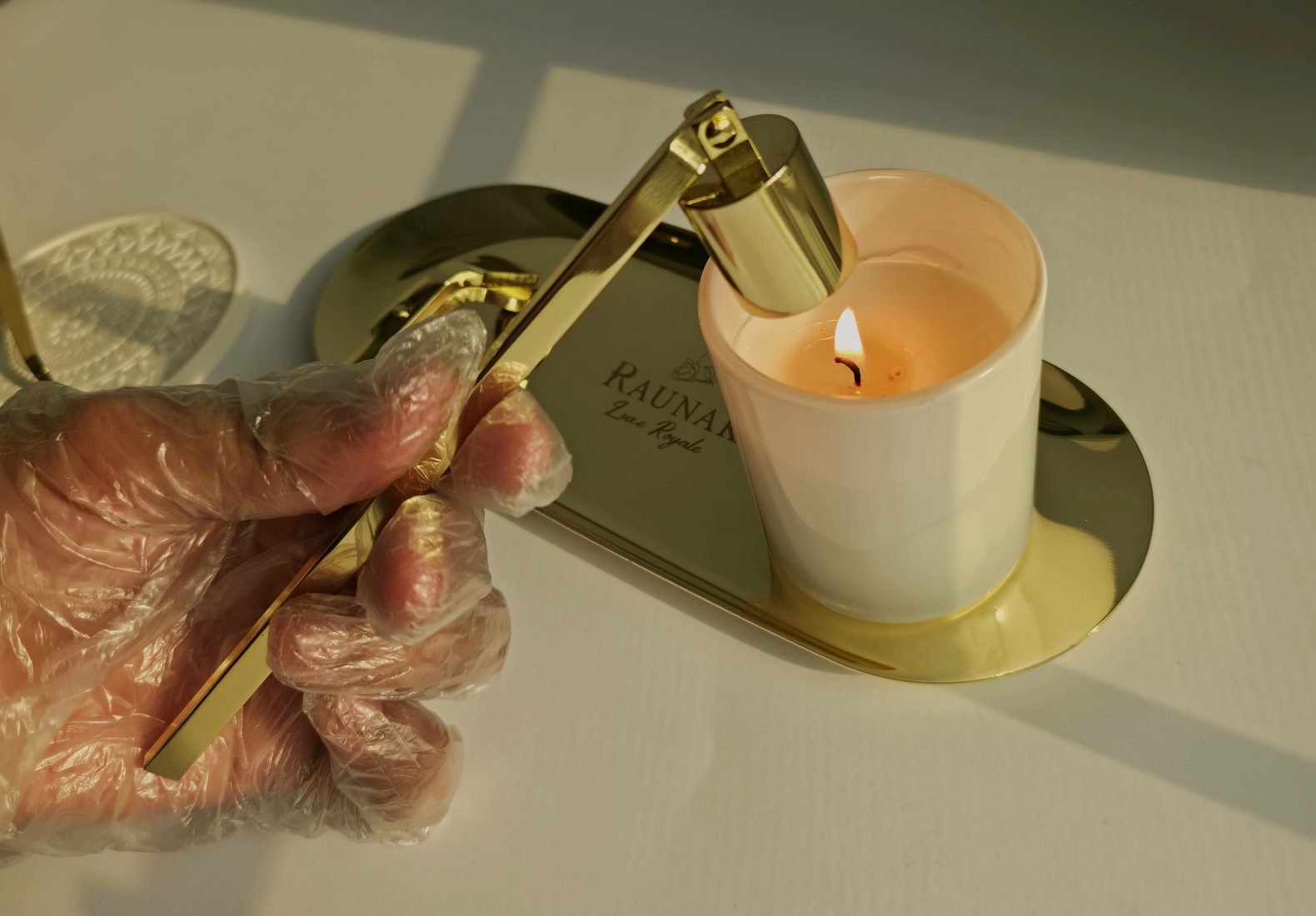 A lit candle on a brass tray with a polished snuffer